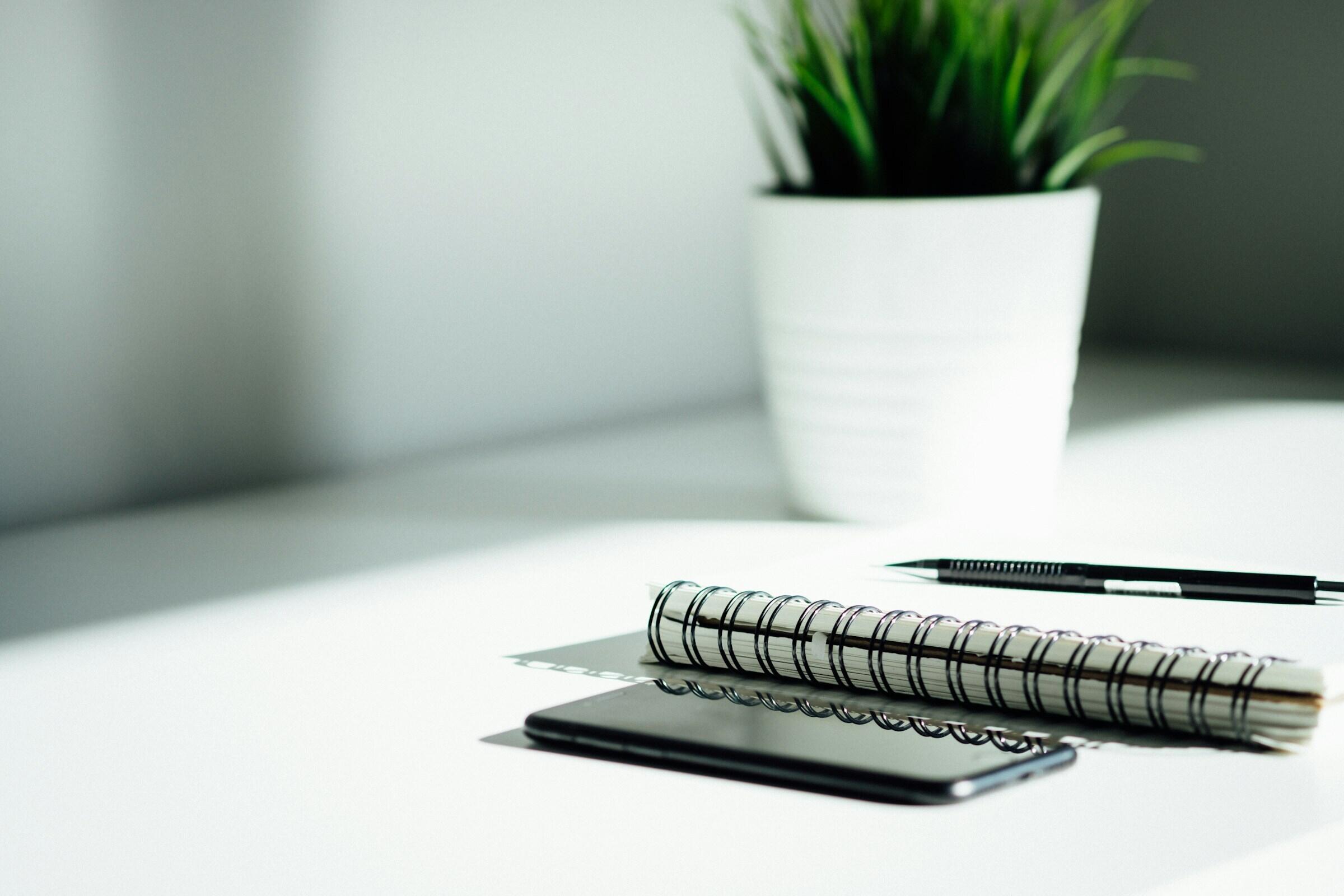 Schreibtisch mit Block, Stift und Pflanze