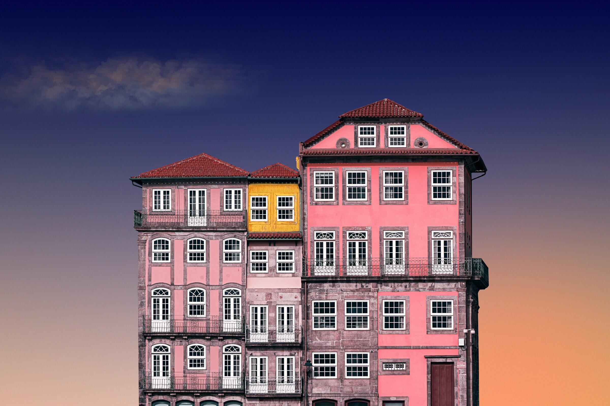 Ein rosfarbenes Gebäude mit mehreren Geschossen vor einem Abendhimmel - schön.