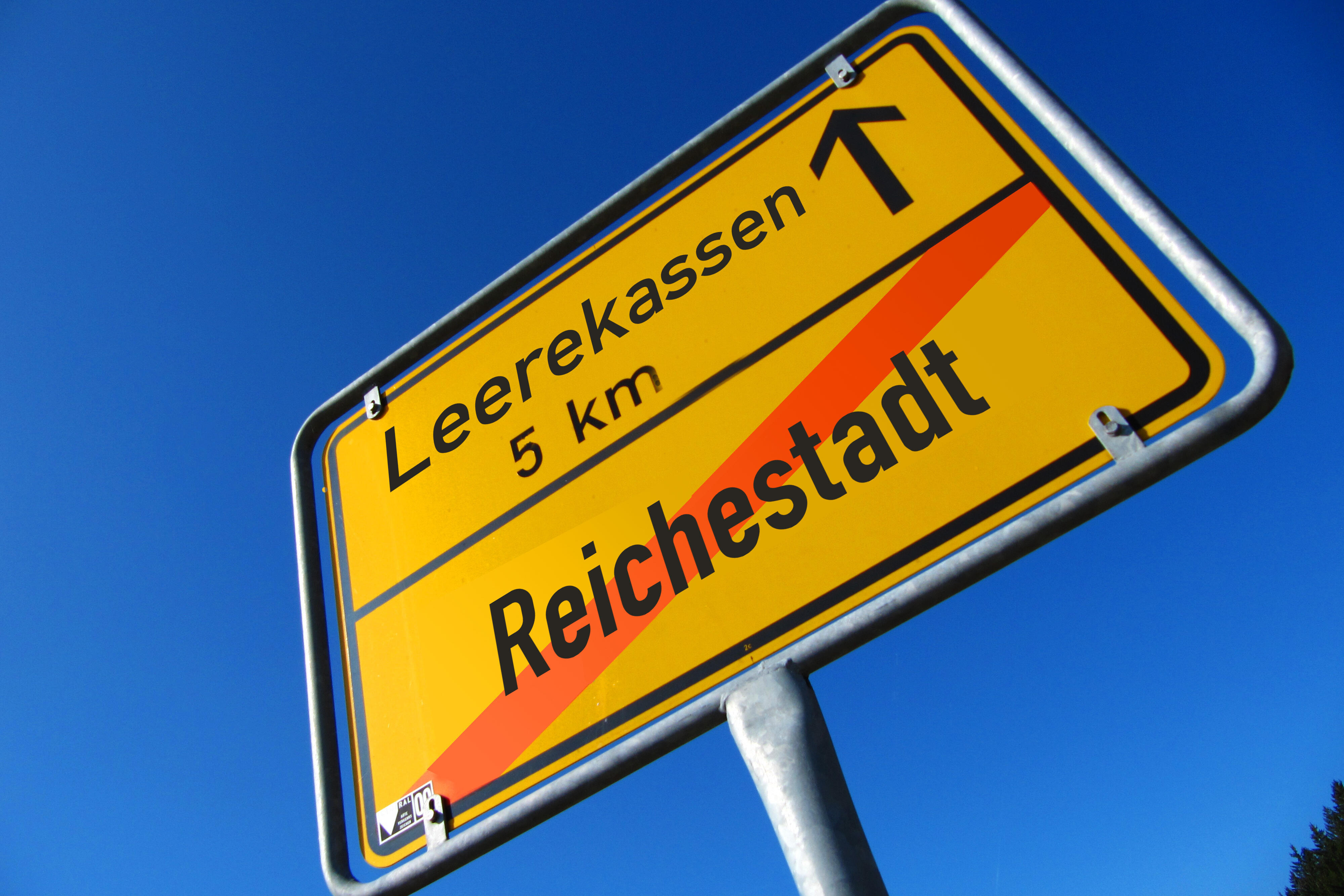 Ein ironisches Ortsschild. Reichestadt ist durchgestrichen. Der Weg führt zu: Leerekassen