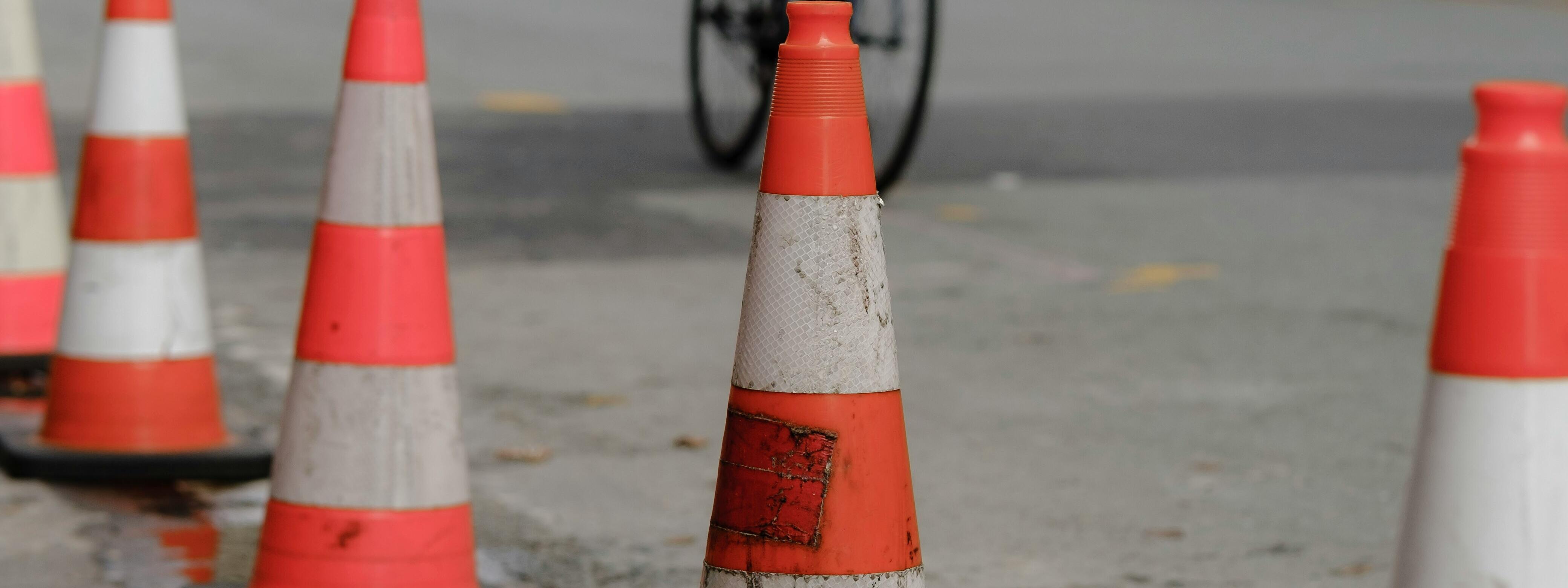 Fahradfahrer auf kaputter Straße mit Pylonen