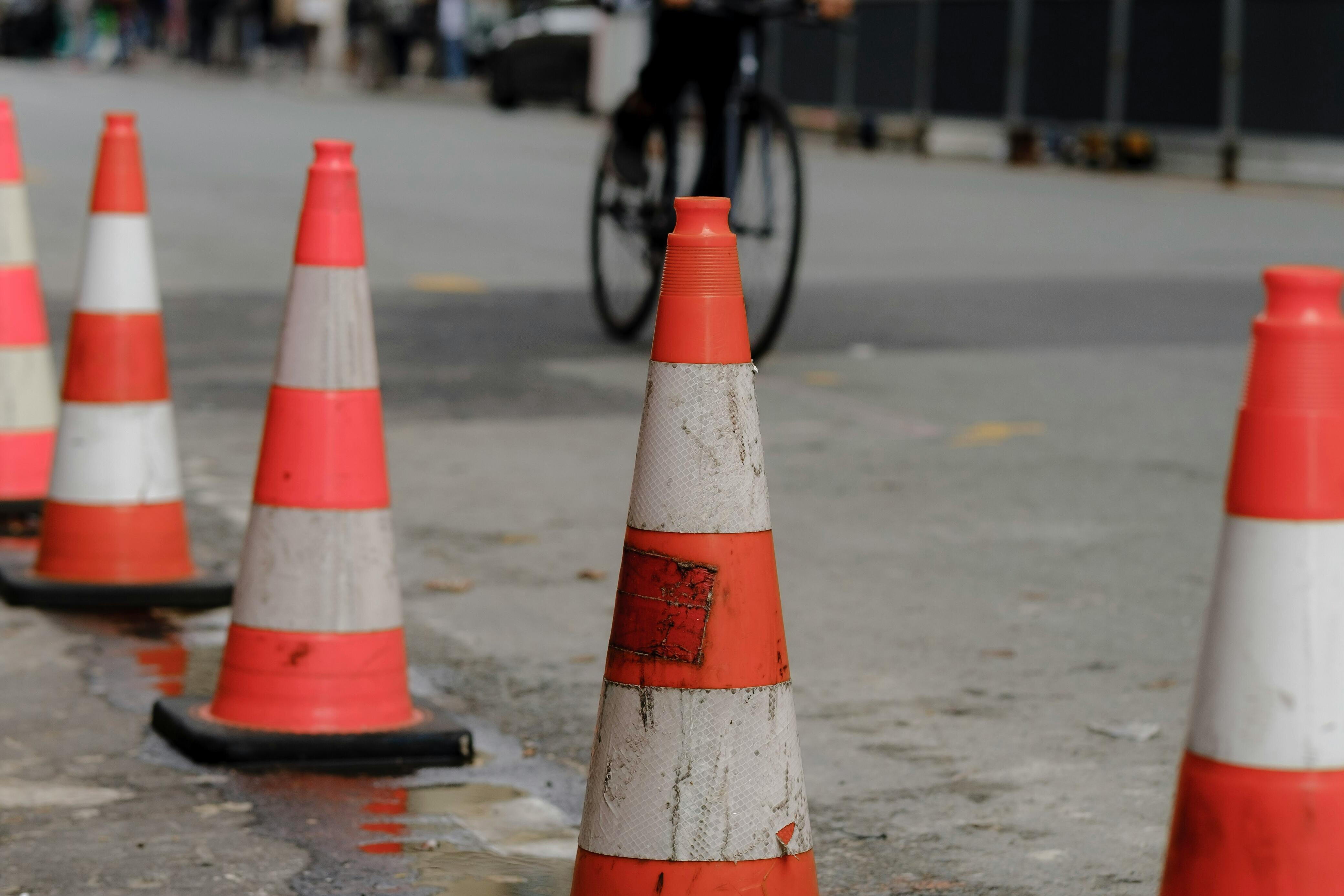 Fahradfahrer auf kaputter Straße mit Pylonen