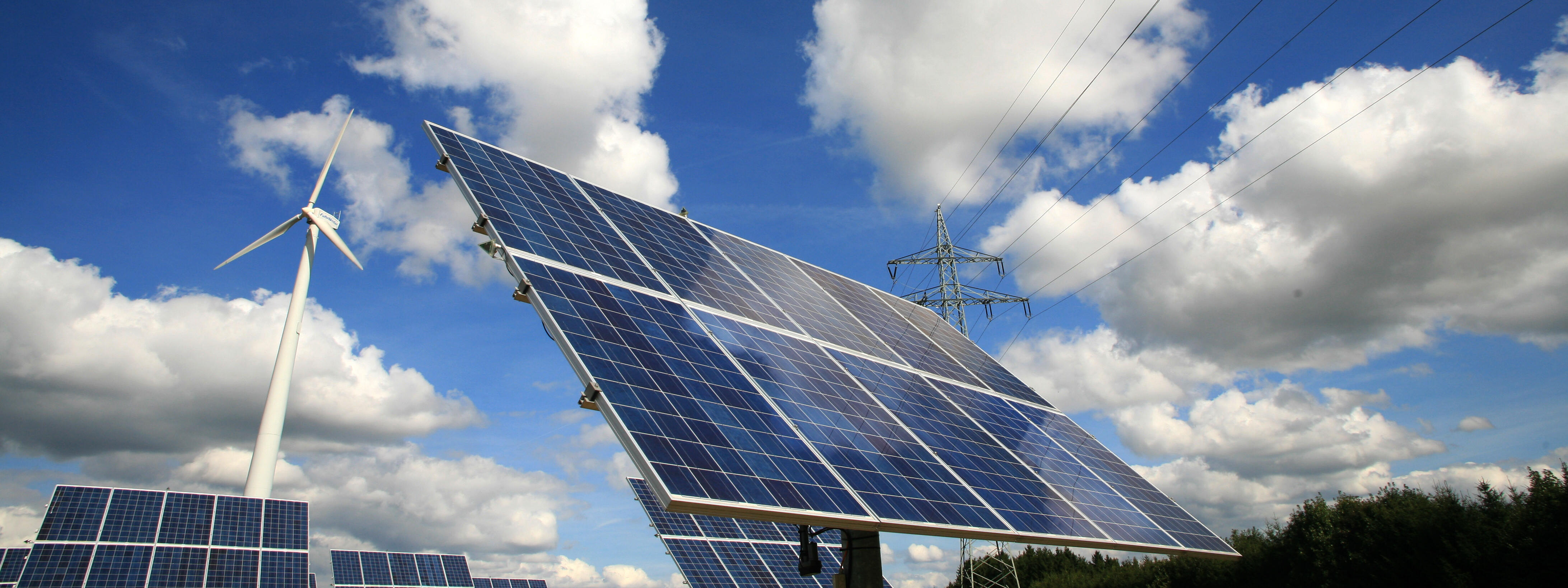 Windrad und Photovoltaikanlage vor wolkigen Himmel