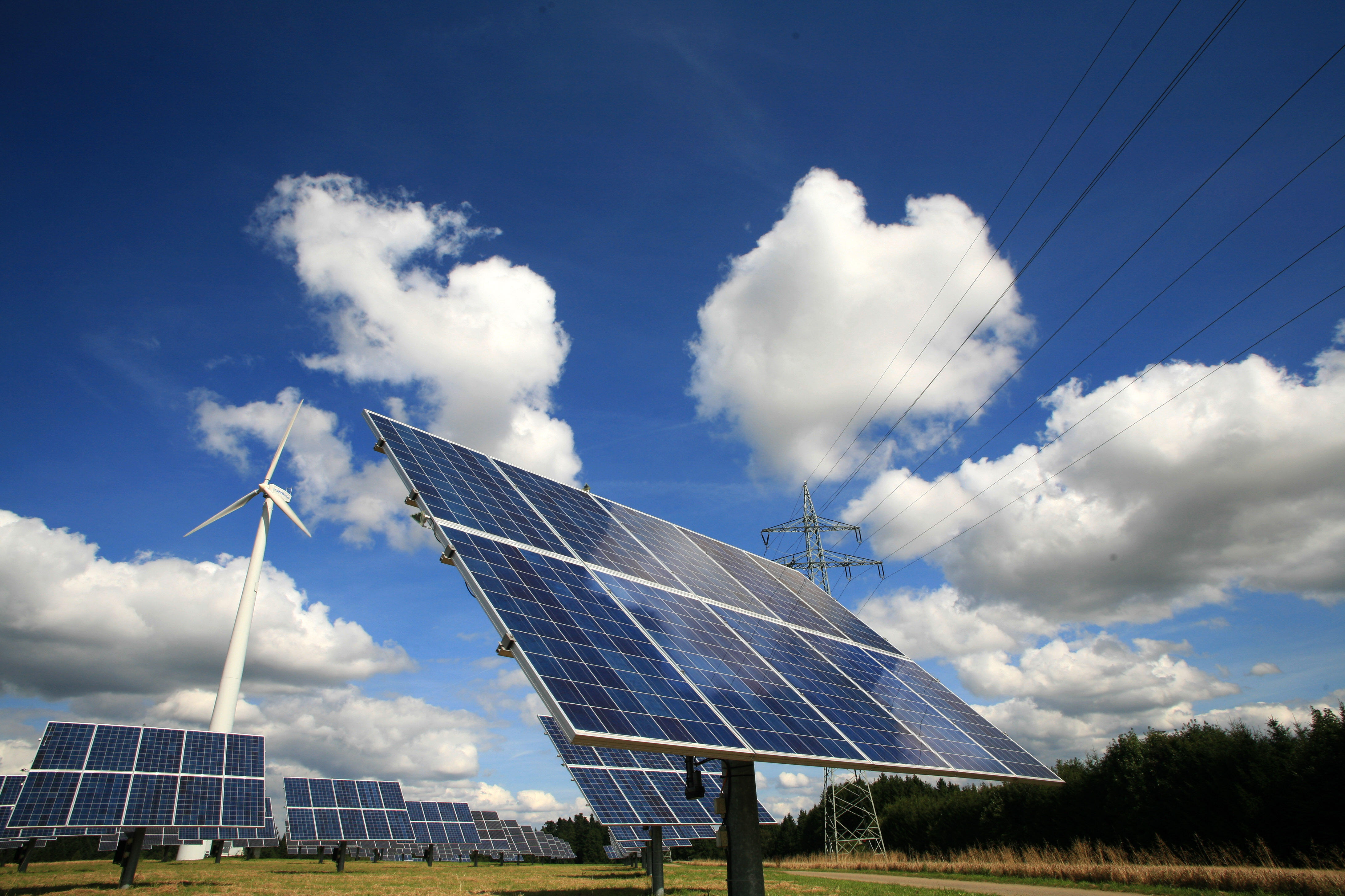 Windrad und Photovoltaikanlage vor wolkigen Himmel