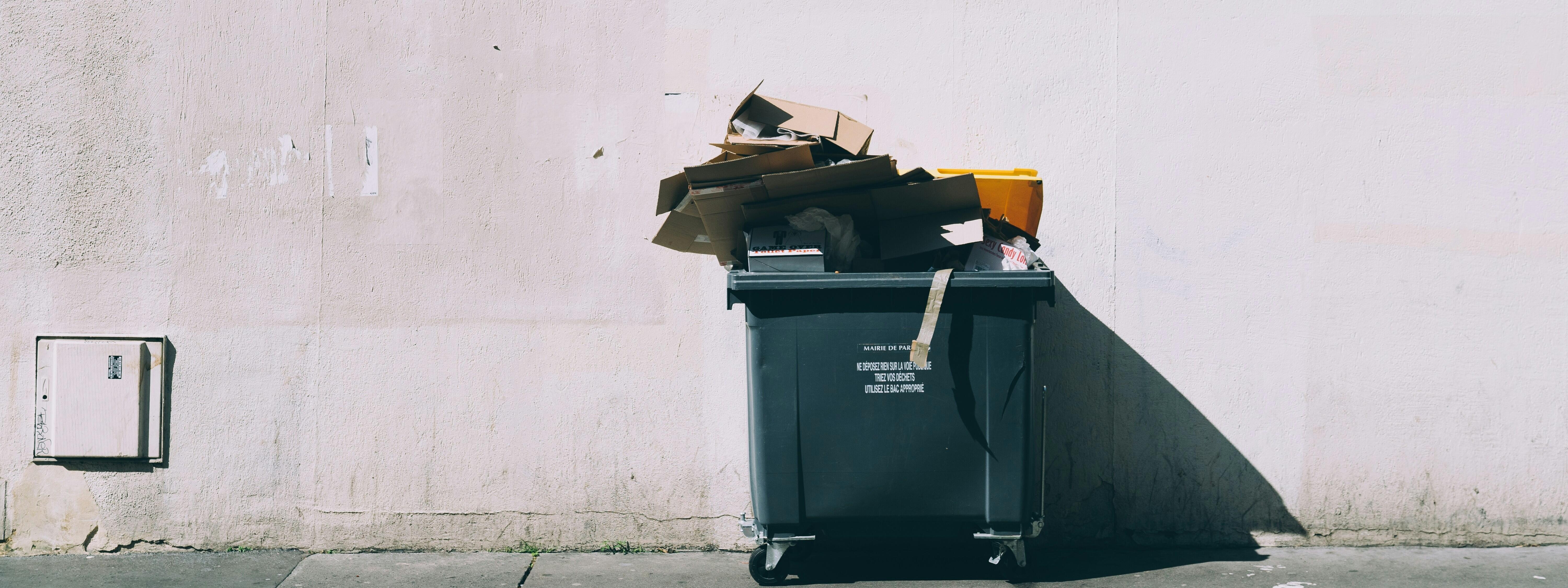 Ein Müllcontainer vor einer hellen Wand