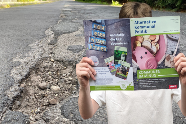 Das Bild einer kaputten Straße. Davor eine Person, die in der neuen Ausgabe der AKP mit dem Titel "Kommunen im Minus" liest.